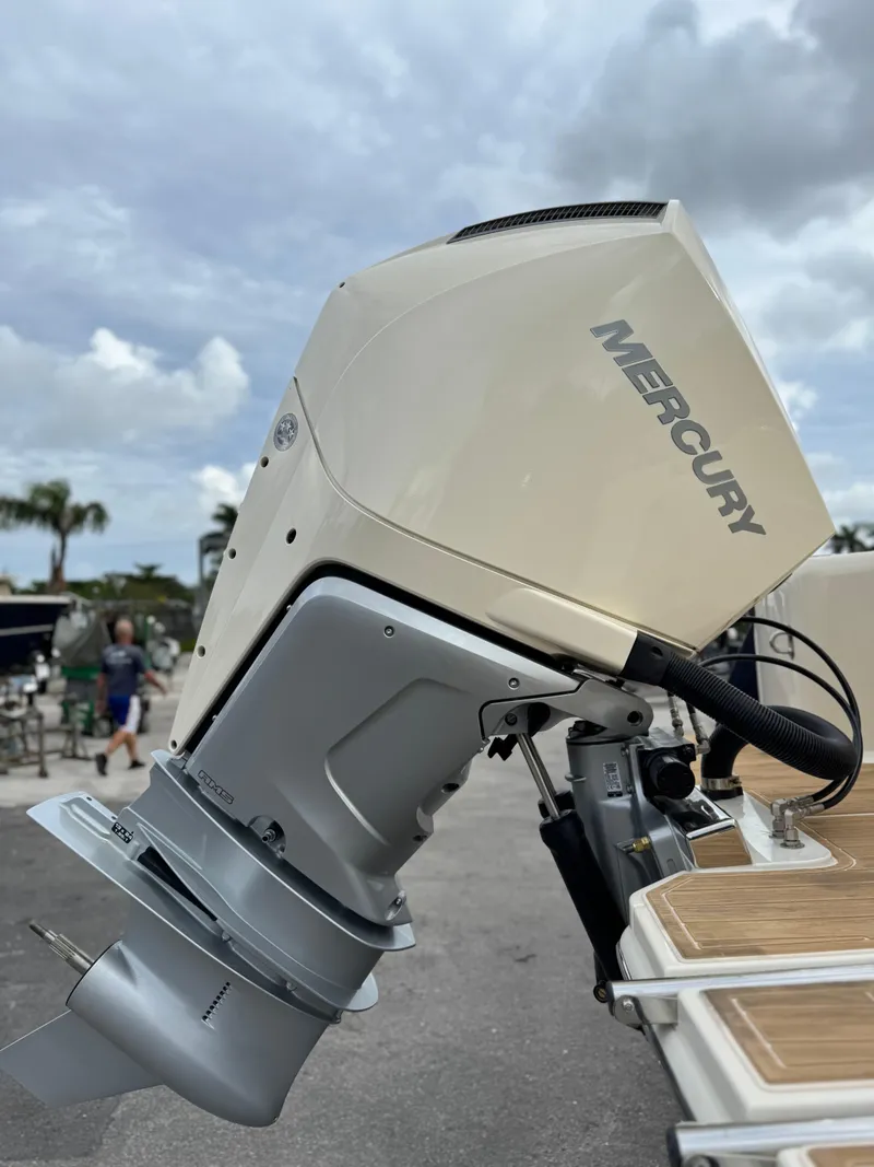 Slide: The Image of 2025 Scout 240 XSF boat with Mercury outboard motor, docked under cloudy skies. - 4