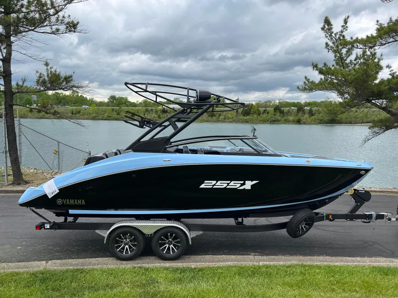 Slide: The Image of 2025 Yamaha Boats 255XD on trailer by a lake, showcasing sleek design and modern features. - 3