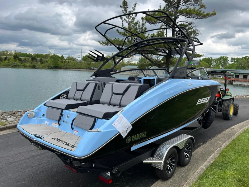 Slide: The Image of 2025 Yamaha Boats 255XD in blue and black on a trailer by a lake. - 4