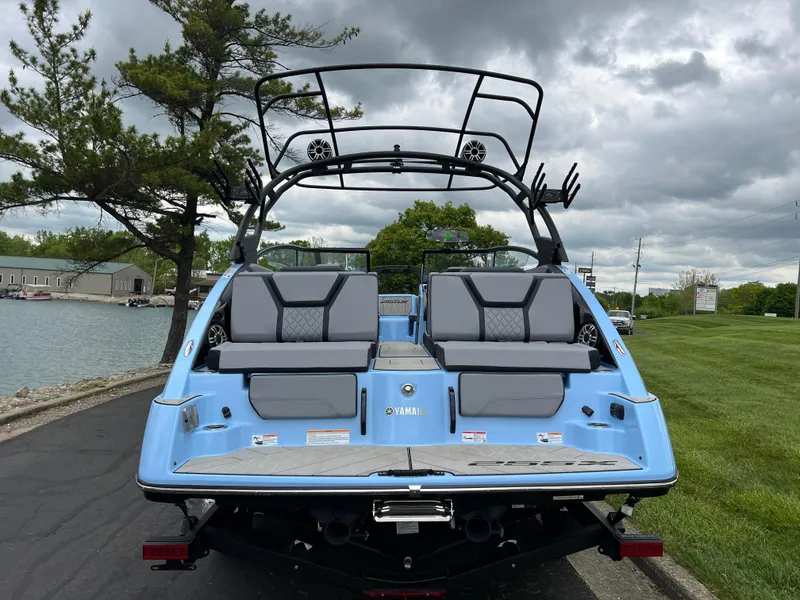 Slide: The Image of 2025 Yamaha Boats 255XD, blue exterior, docked near a lake under cloudy skies. - 5