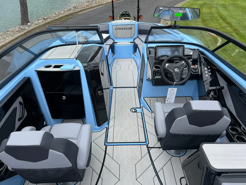 Slide: The Image of 2025 Yamaha Boats 255XD interior with modern dashboard and seating, docked by a lake. - 9