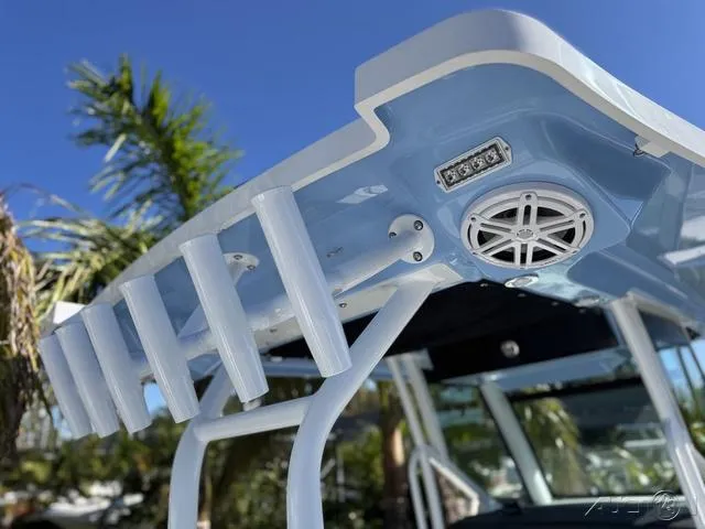 Slide: The Image of 2025 Blackfin 272CC boat with rod holders and speaker, under a clear blue sky. - 15