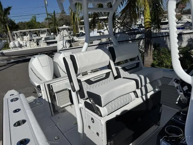 Slide: The Image of 2025 Blackfin 272CC boat with white seating and dual engines, docked near palm trees. - 37