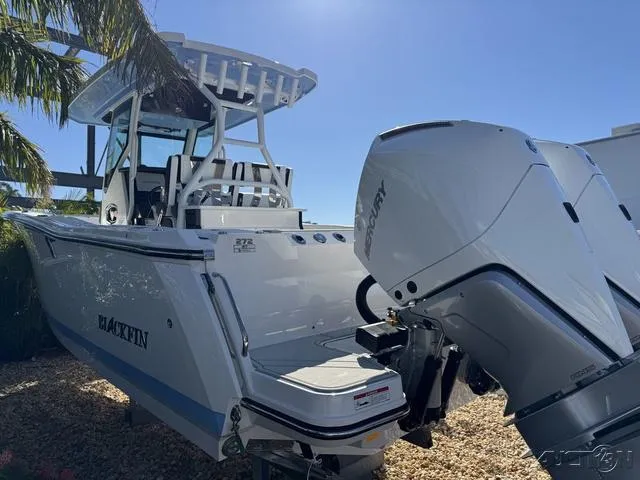 Slide: The Image of 2025 Blackfin 272CC boat with Mercury outboard engine, docked under palm trees. - 6