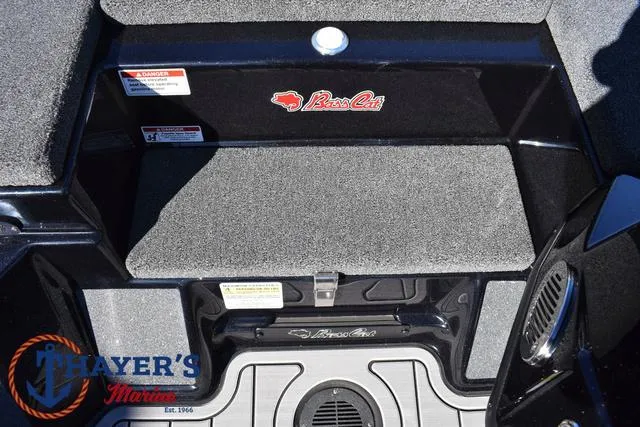 Slide: The Image of 2025 Bass Cat Cougar FTD boat interior with storage compartment and Thayer's Marine logo. - 21