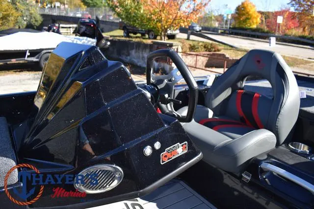 Slide: The Image of 2025 Bass Cat Cougar FTD boat interior with steering wheel and seat, outdoors in autumn setting. - 30