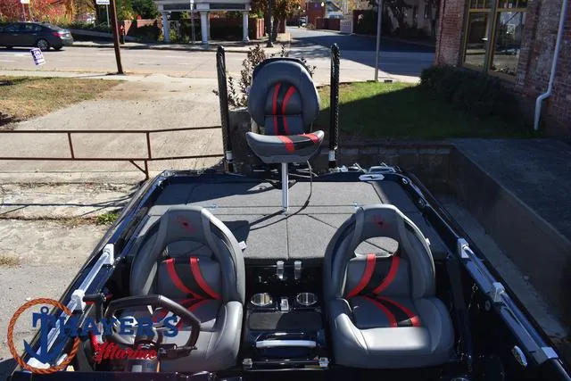 Slide: The Image of 2025 Bass Cat Cougar FTD boat interior with gray and red seats, parked outdoors. - 37