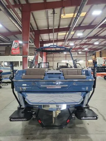 Slide: The Image of 2024 Malibu 23 LSV boat in showroom, rear view, blue exterior, spacious seating. - 3