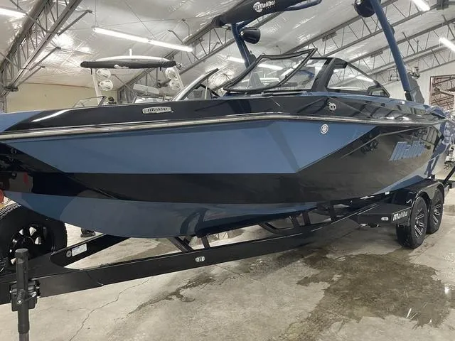 Slide: The Image of 2024 Malibu 23 LSV boat in showroom, blue and black design, on trailer. - 8