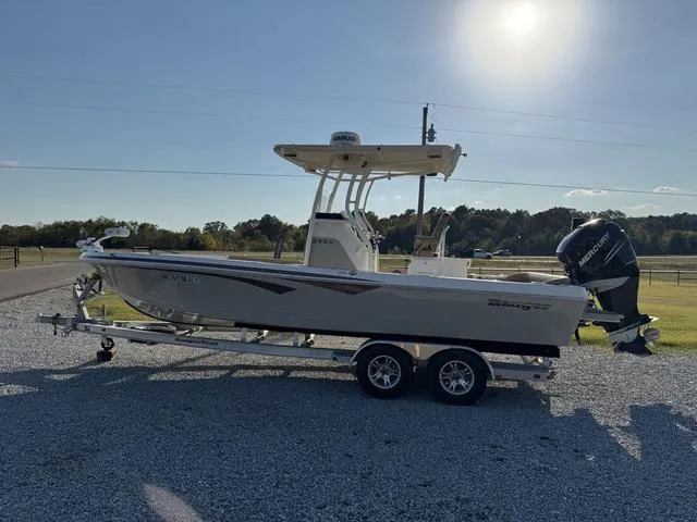 Slide: The Image of 2018 Ranger 2350 Bay boat on trailer, parked outdoors under sunny sky. - 4