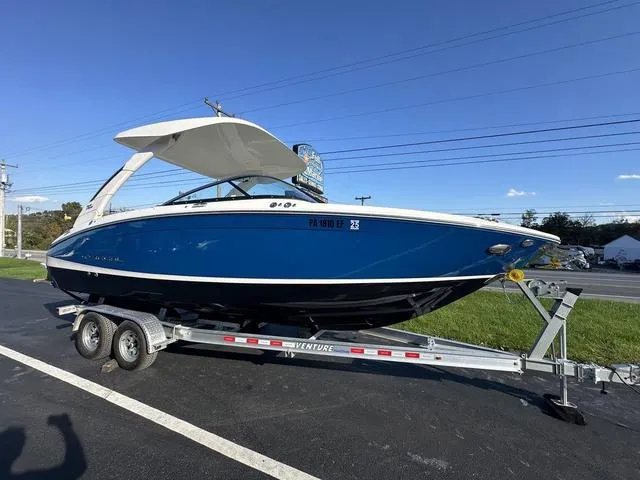Slide: The Image of 2023 Regal LS6 boat on trailer, blue hull, parked outdoors. - 1