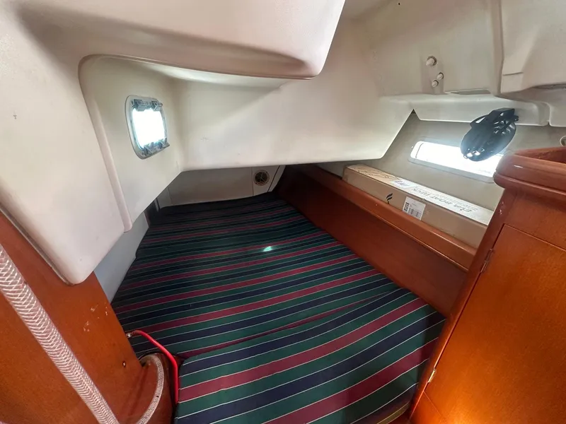 Slide: The Image of Interior cabin of 2006 Beneteau 393 sailboat with striped bedding and wooden accents. - 22