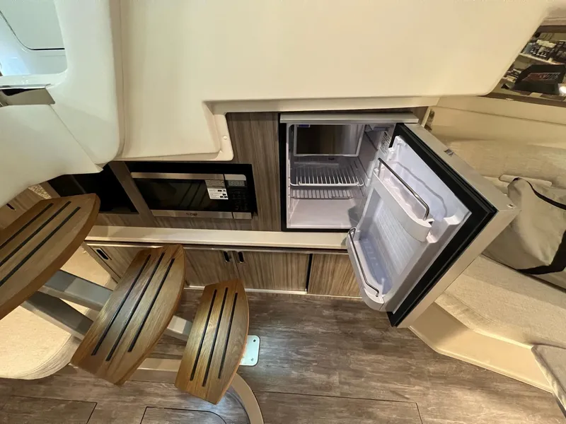 Slide: The Image of 2025 Sea Ray Sundancer 320 Coupe interior with open fridge and wooden steps. - 19