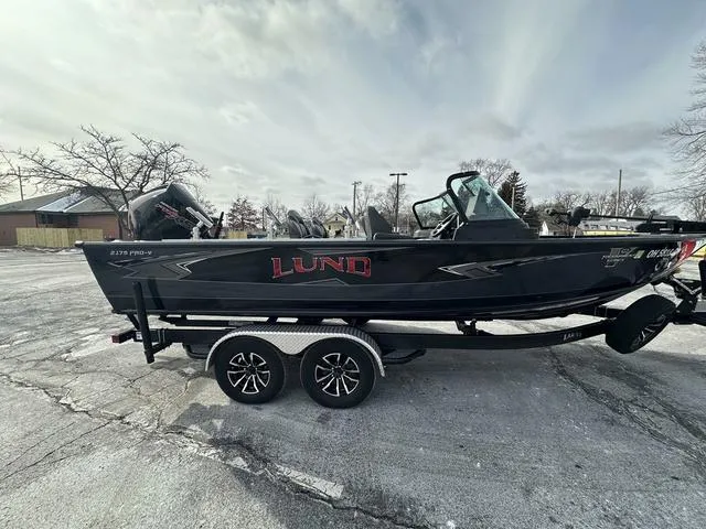 Slide: The Image of 2024 Lund 2175 Pro-V Sport boat on trailer by a lakeside. - 4