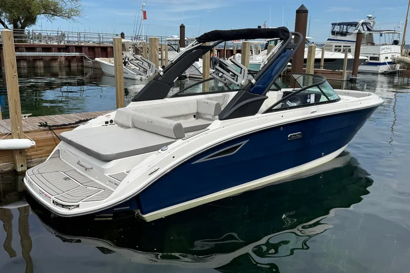 The Image of 2025 Sea Ray SDX 250 Surf boat docked in a marina, featuring sleek design and modern amenities. - 0