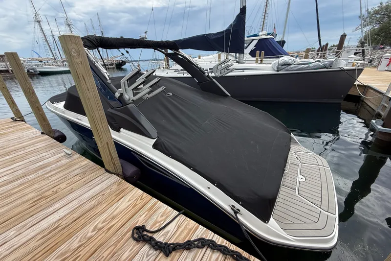 Slide: The Image of 2025 Sea Ray SDX 250 Surf boat docked with black cover, marina background. - 17