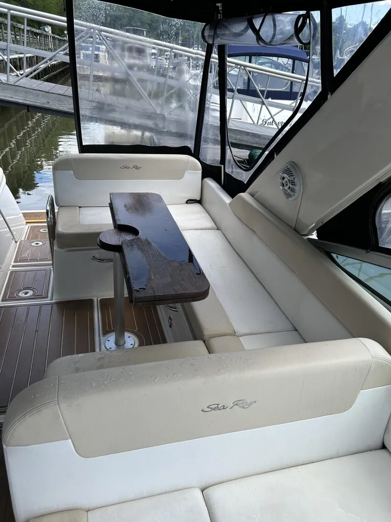 Slide: The Image of 2013 Sea Ray 370 Venture boat interior with cushioned seating and wooden table. - 6