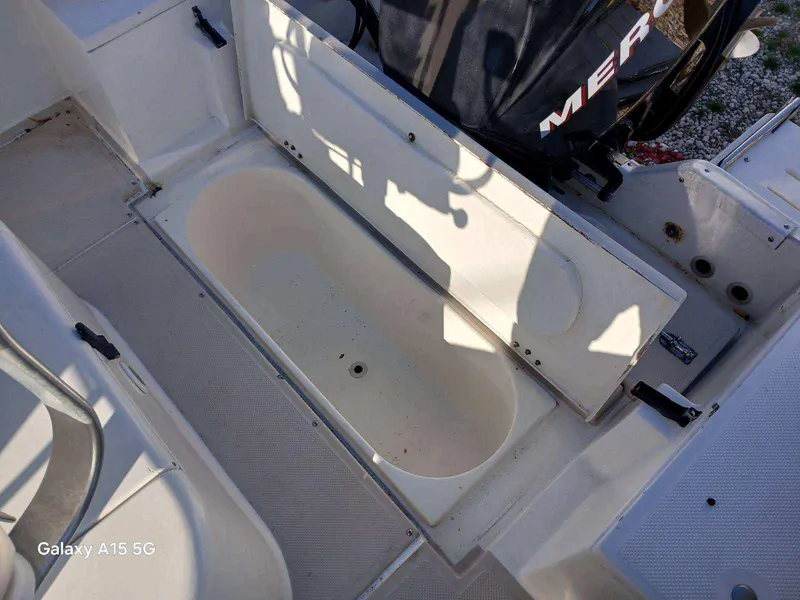 Slide: The Image of 1994 Robalo 23 boat interior with open storage compartment and Mercury Optimax outboard engine. - 12
