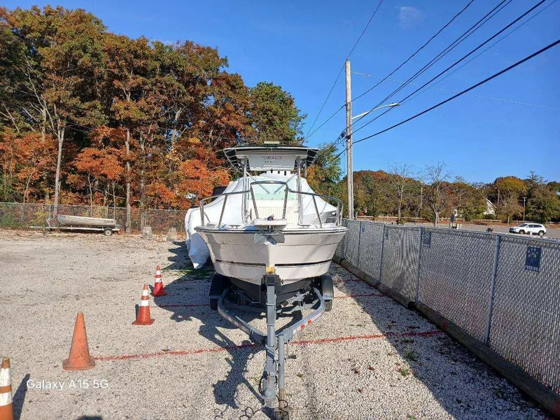 Slide: The Image of 1994 Robalo 23 boat with Merc Optimax 225 outboard, parked on gravel lot. - 4