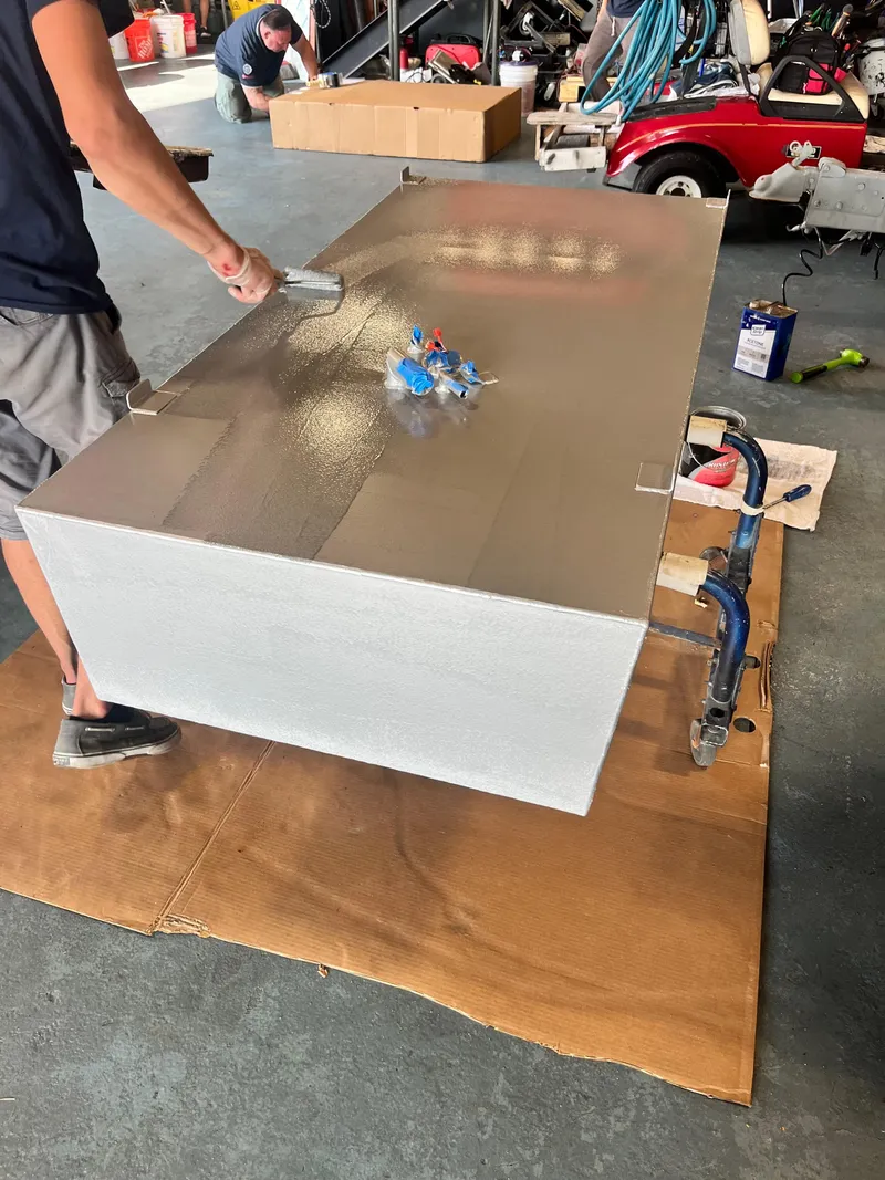 Slide: The Image of Person working on a large metal sheet in a garage setting. - 34