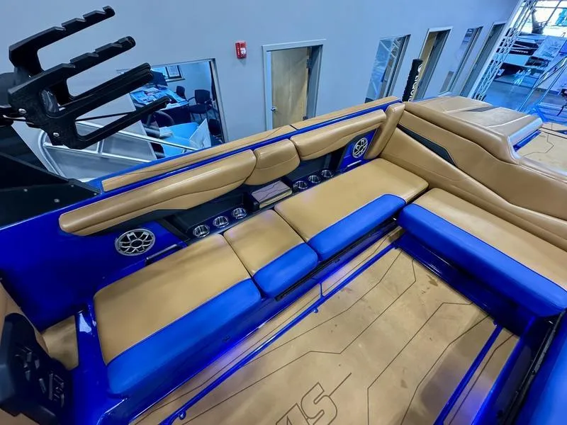 Slide: The Image of 2022 Axis T250 boat interior with blue and tan seating, speakers, and storage compartments. - 13