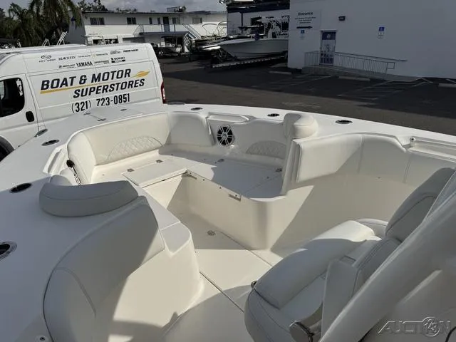 Slide: The Image of 2025 Key West 263 FS boat interior with speakers and seating, parked near a dealership van. - 36