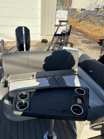 Slide: The Image of 2022 Starcraft MX 25 Q DC Tritoon with seating and table, featuring cup holders. - 11