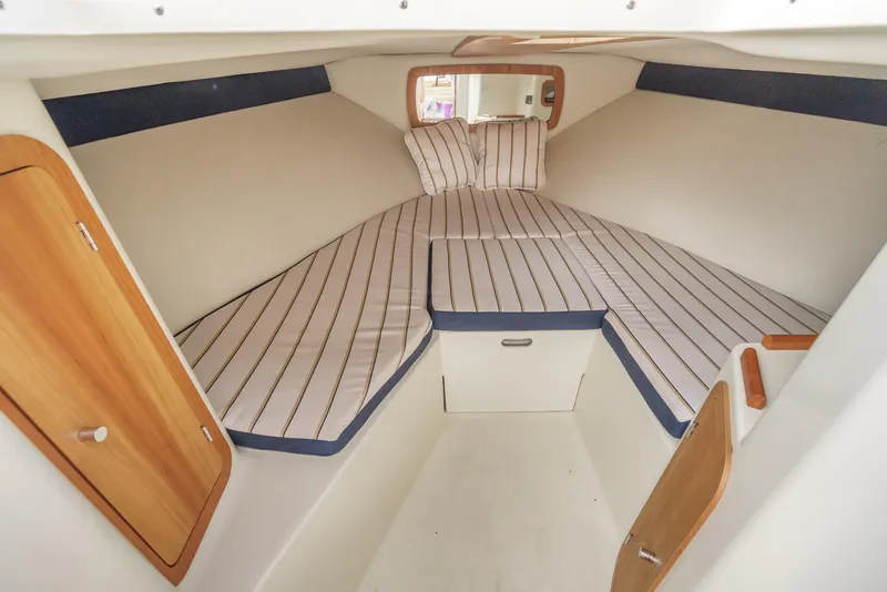 Slide: The Image of 2012 Chris-Craft Corsair 28 cabin interior with striped bedding and wooden accents. - 24