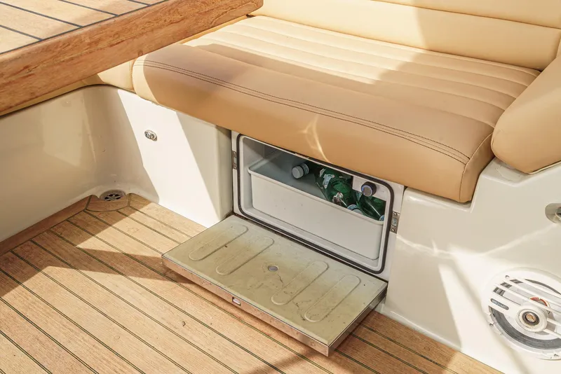 Slide: The Image of 2012 Chris-Craft Corsair 28 interior with built-in cooler and beige seating. - 32
