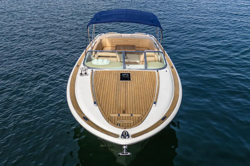 Slide: The Image of 2012 Chris-Craft Corsair 28 boat with teak deck and blue canopy on water. - 6