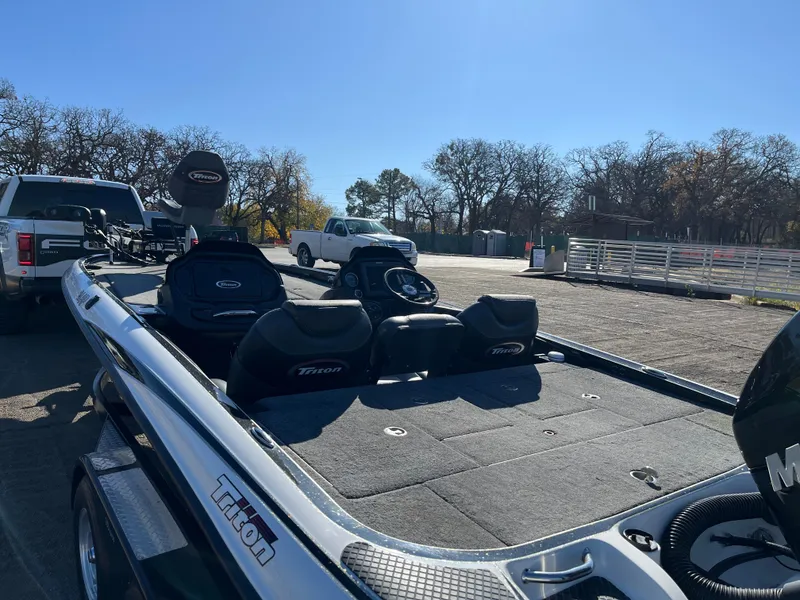 Slide: The Image of 2013 Triton 21 HP boat on trailer, parked outdoors under clear blue sky. - 11