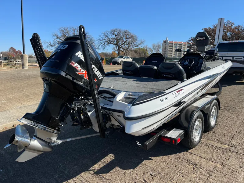Slide: The Image of 2013 Triton 21 HP boat with Mercury engine on trailer, parked outdoors. - 21