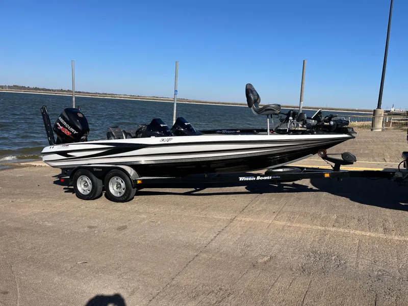 Slide: The Image of 2013 Triton 21 HP boat on trailer by the water. - 24