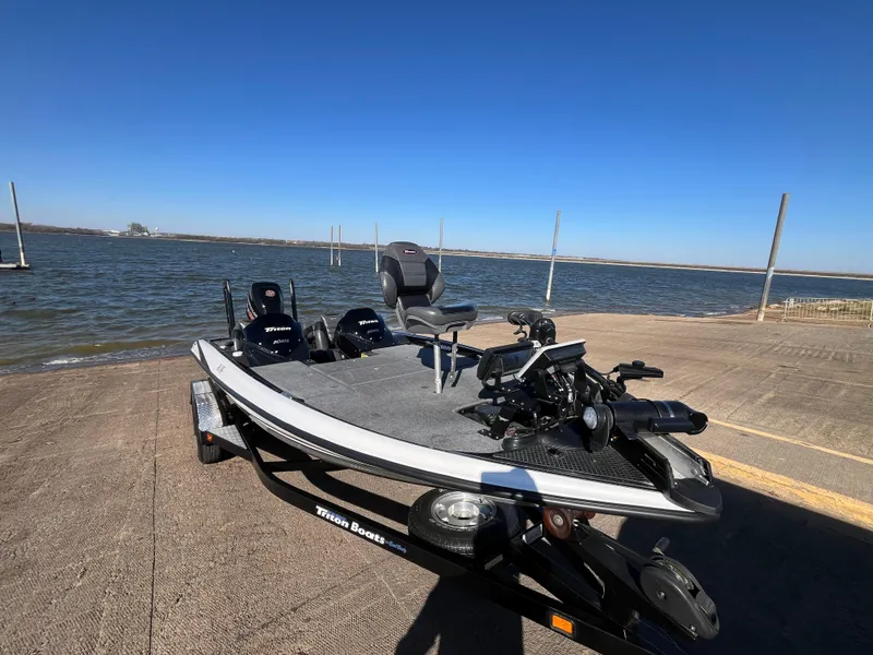 Slide: The Image of 2013 Triton 21 HP boat on a lakeside ramp under clear blue skies. - 25