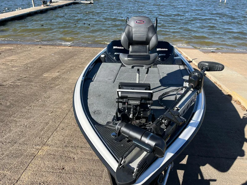 Slide: The Image of 2013 Triton 21 HP boat at lakeside dock, featuring advanced navigation equipment. - 27