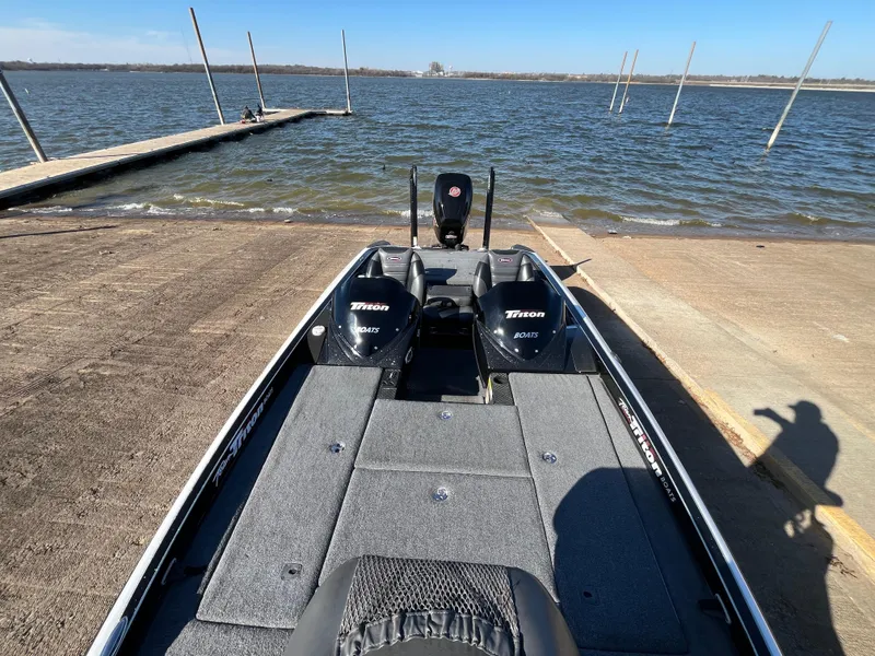 Slide: The Image of 2013 Triton 21 HP boat at a lakeside dock, ready for launch. - 28