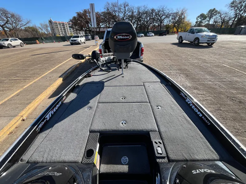 Slide: The Image of 2013 Triton 21 HP boat in parking lot, showcasing spacious deck and seating. - 31