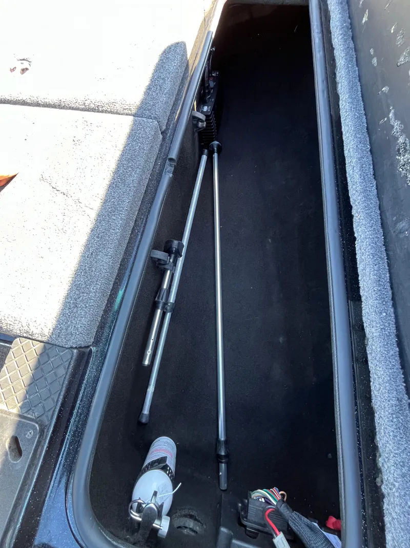 Slide: The Image of 2013 Triton 21 HP boat storage compartment with fishing rods and equipment. - 36