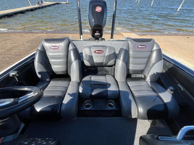 Slide: The Image of 2013 Triton 21 HP boat interior with three black seats by the water. - 39