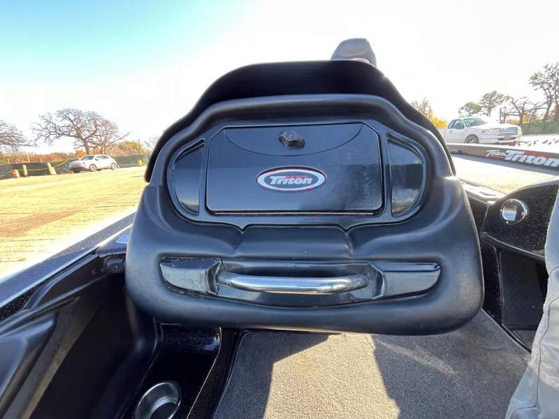 Slide: The Image of 2013 Triton 21 HP boat dashboard with logo, black interior, and outdoor setting. - 46