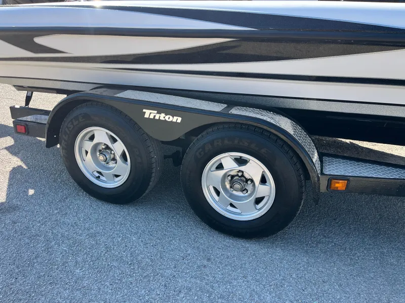 Slide: The Image of 2013 Triton 21 HP boat trailer with dual wheels on asphalt. - 56