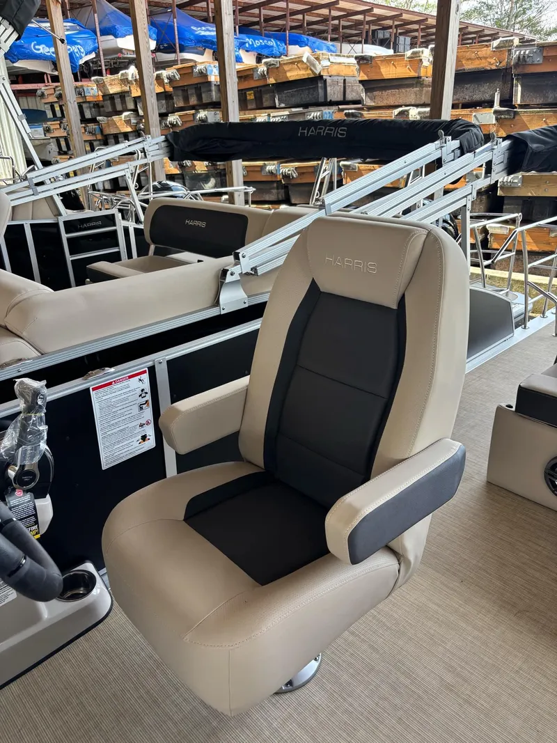 Slide: The Image of 2025 Harris CRUISER 230 SLDH boat seat, beige and black, in a showroom setting. - 8
