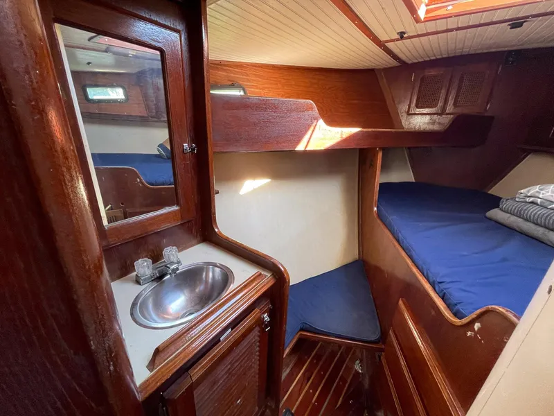 Slide: The Image of 1983 Islander Freeport yacht cabin with wooden interior, bunk beds, and compact sink area. - 14