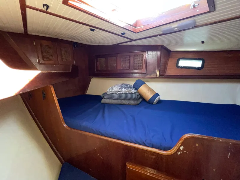 Slide: The Image of 1983 Islander Freeport cabin with blue bedding and wooden interior. - 15