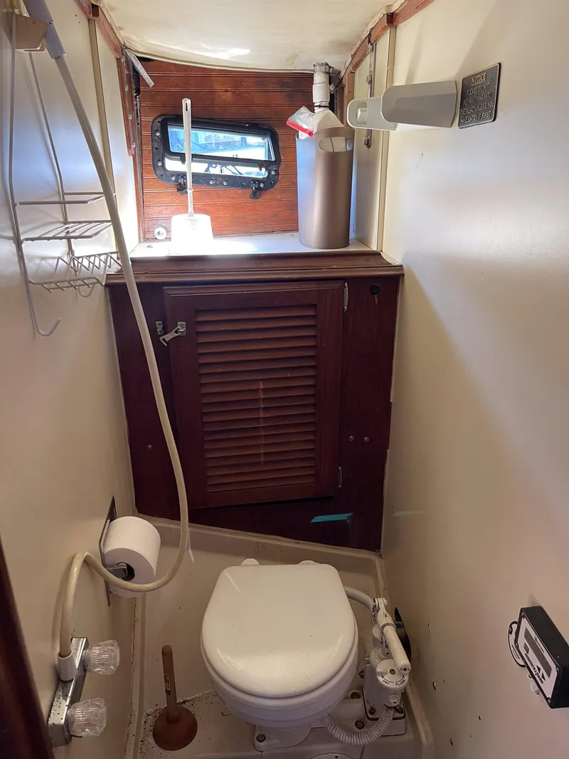 Slide: The Image of 1983 Islander Freeport boat bathroom with toilet, wooden cabinet, and small window. - 16