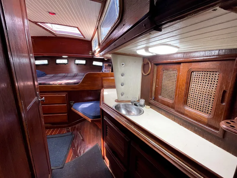 Slide: The Image of Interior of 1983 Islander Freeport sailboat with wood paneling and compact kitchen area. - 20