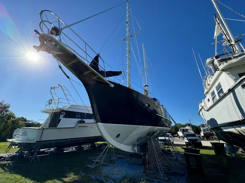 Slide: The Image of 1983 Islander Freeport sailboat on land, sunlit, with clear blue sky. - 38