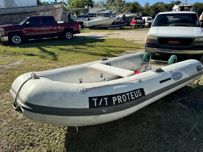 Slide: The Image of Inflatable boat labeled "T/T Proteus" on grass, with trucks and boats in the background. - 40