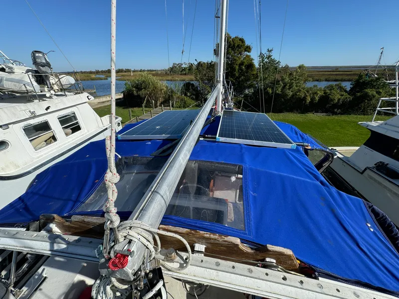 Slide: The Image of 1983 Islander Freeport sailboat with blue cover and solar panels on deck. - 44