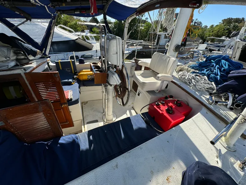 Slide: The Image of 1983 Islander Freeport sailboat cockpit with steering wheel, seating, and nautical equipment. - 45